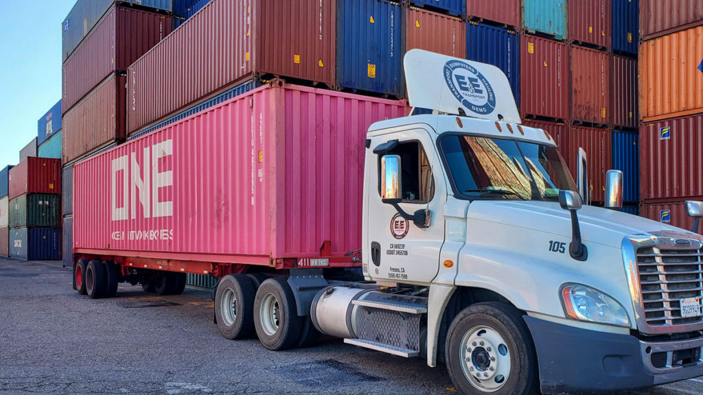 A shipping container being delivered by a diesel truck operated by E&E Transport of Fresno, CA